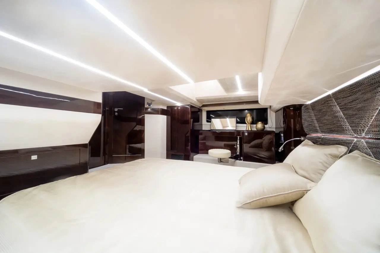 Luxury yacht interior featuring a spacious bedroom, sleek furniture, and ambient lighting. Plush bedding and pillows visible.