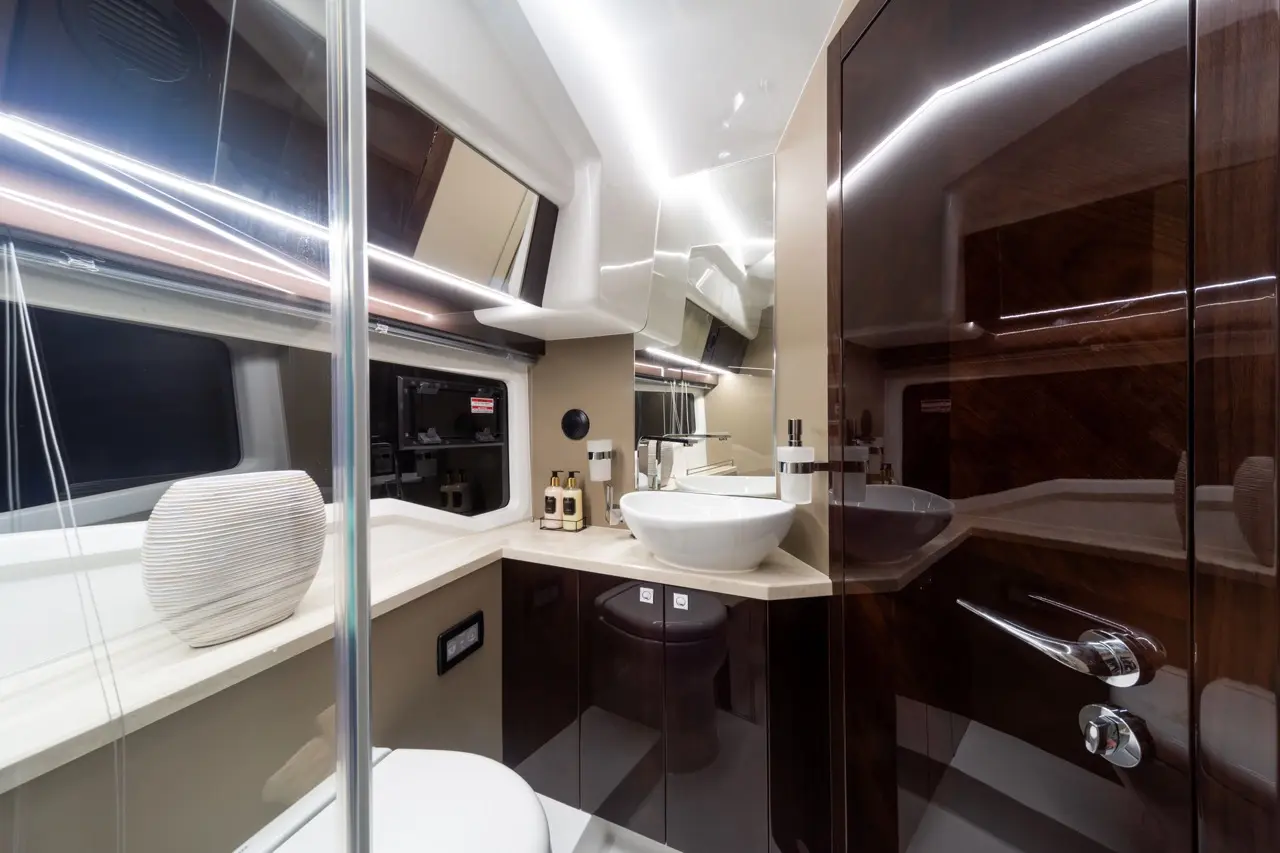 A modern bathroom featuring a white basin, large mirror, stylish dark cabinetry, and elegant lighting.