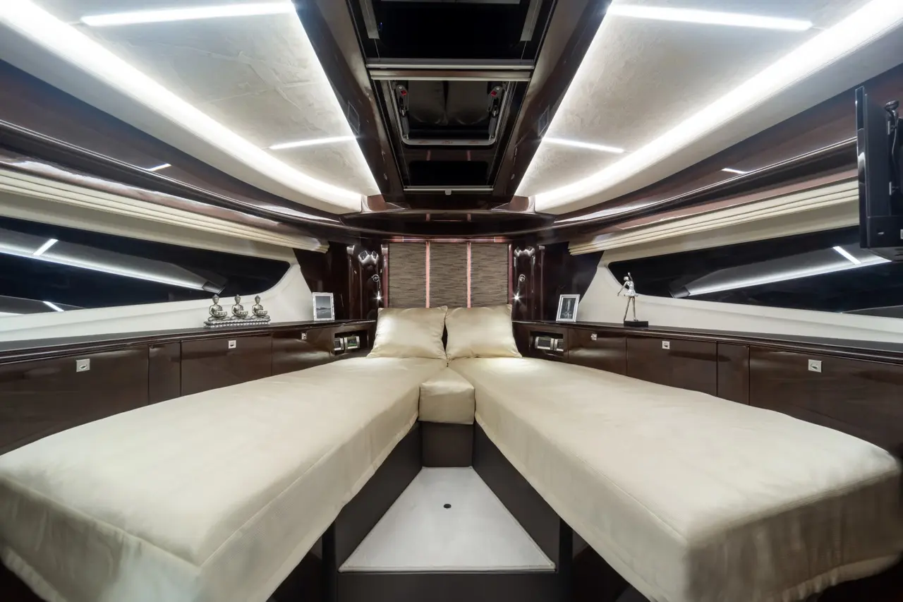 Luxurious yacht interior featuring two cream-coloured beds, sleek wood finishes, and ambient lighting, with decorative elements.