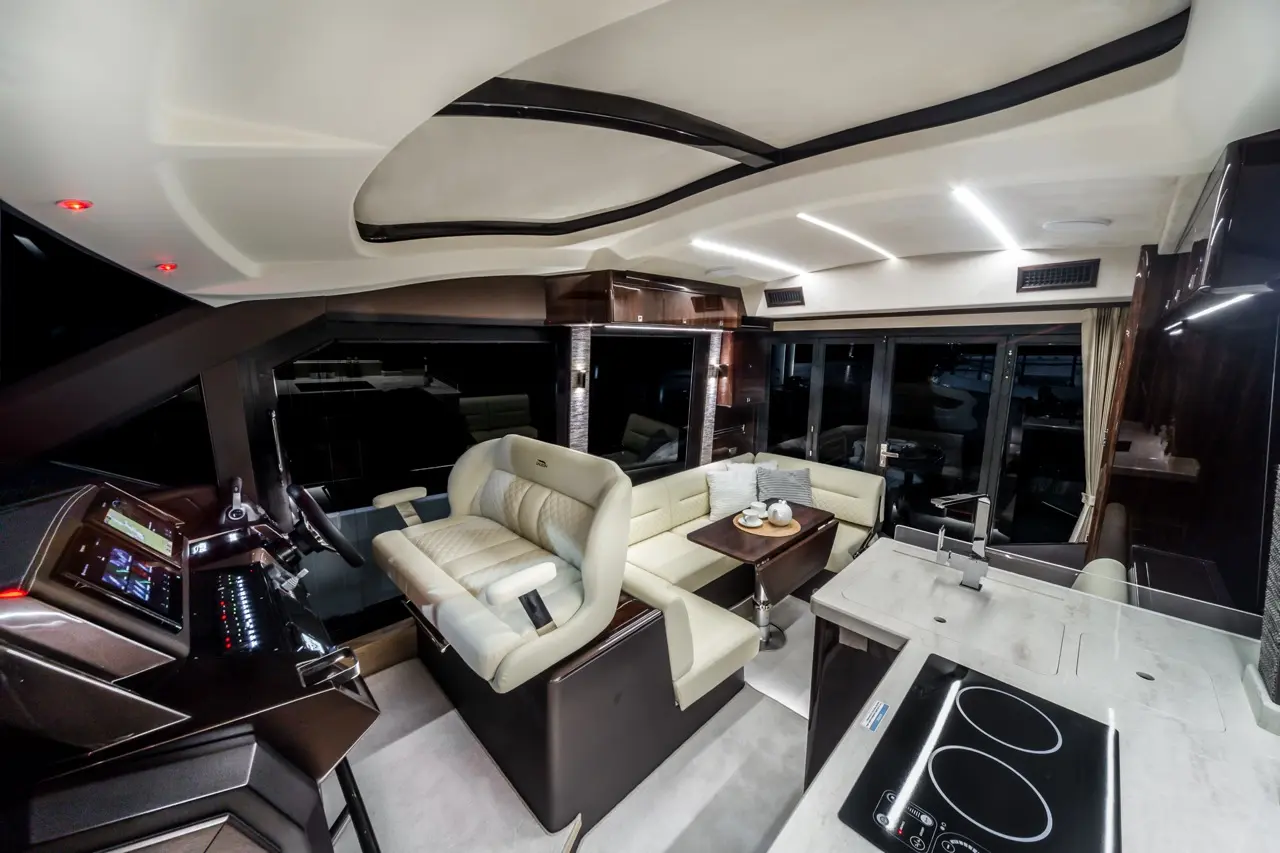 Luxurious interior of a yacht featuring a modern helm, plush seating, and a sleek kitchenette with a stove and dining table.