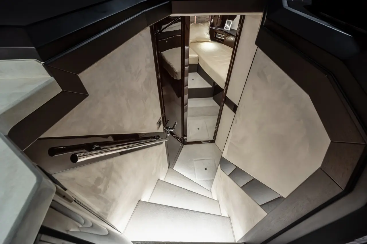 Staircase leading down to a stylish cabin with a bed, illuminated by soft lighting and modern finishes.