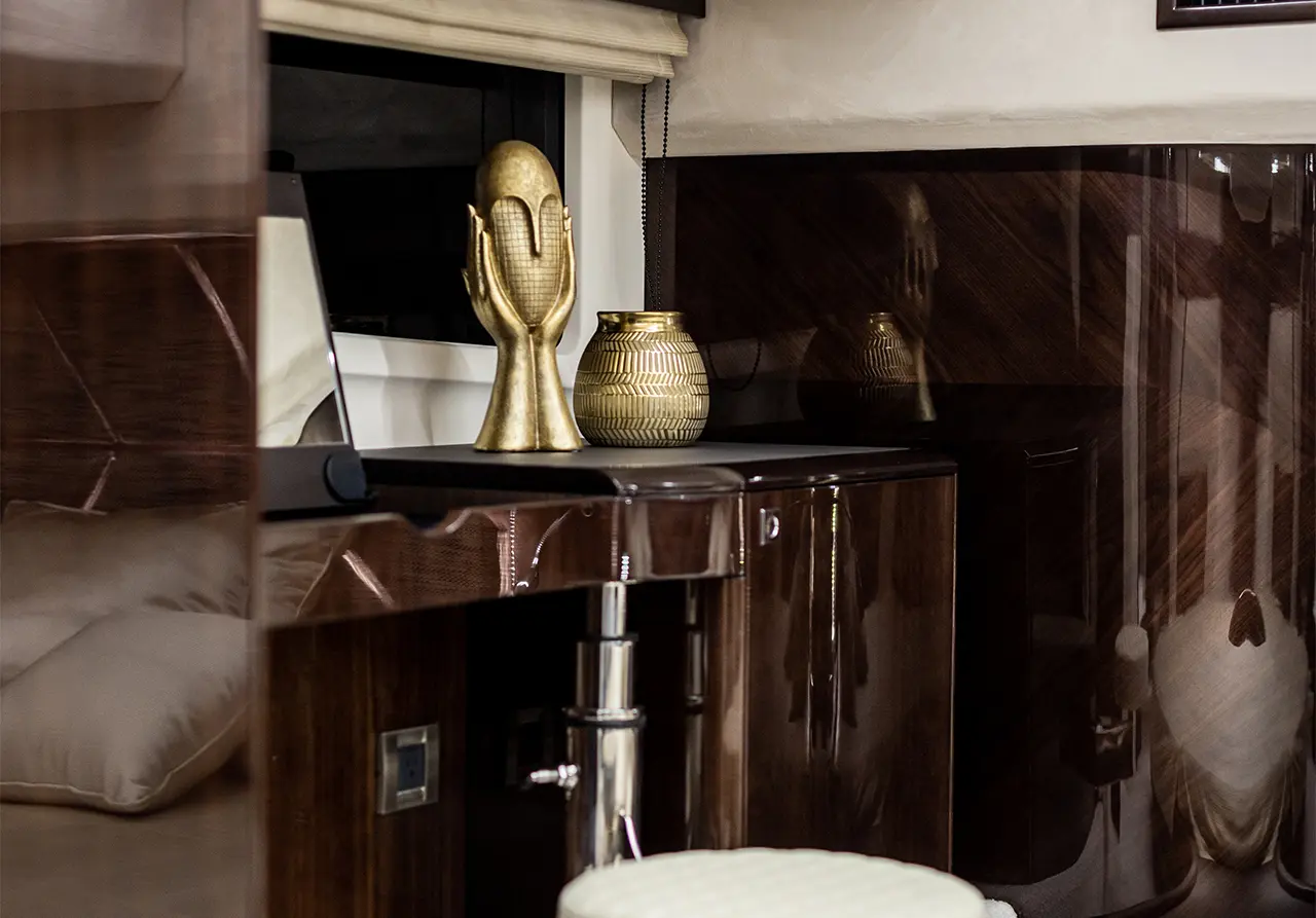 Stylish interior featuring a gold decorative sculpture, patterned vase, and polished wood furniture in an elegant setting.