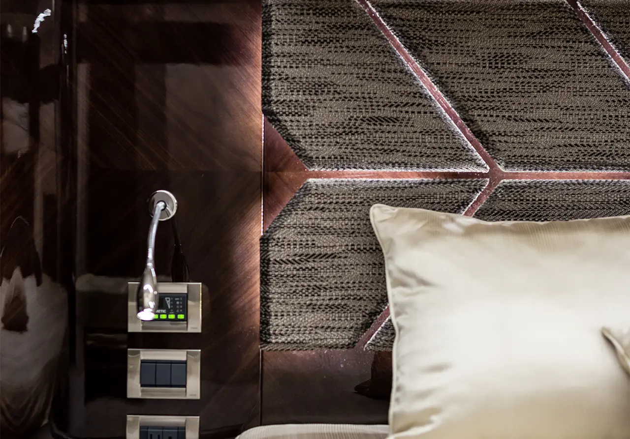 Elegant headboard with geometric design, bedside control panel, and stylish pillow in a modern bedroom setting.