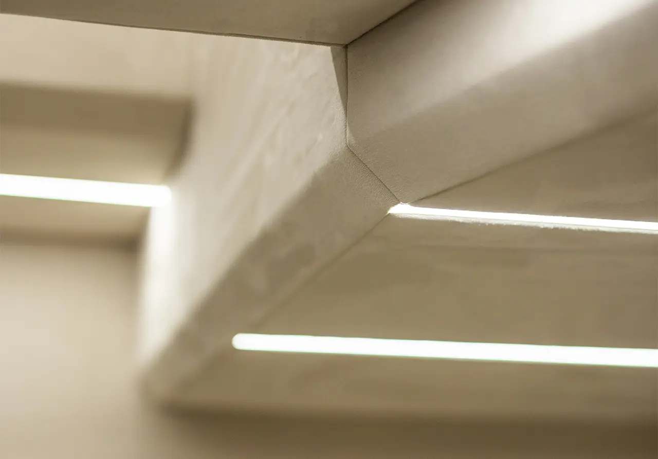 Close-up of a modern ceiling feature with soft LED lighting and smooth, curved concrete edges, highlighting contemporary design.