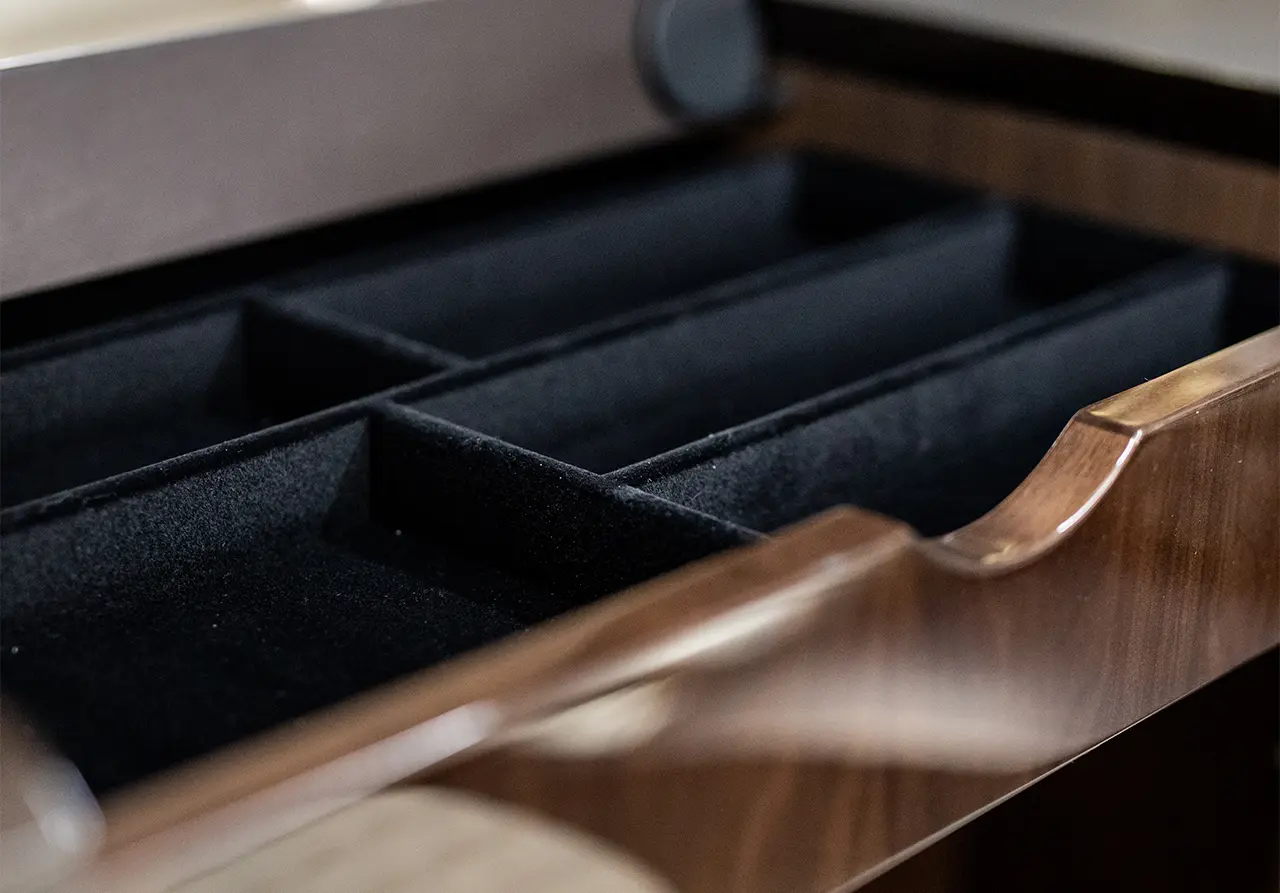 Close-up of a wooden drawer interior with black velvet compartments for organizing items. Ideal for storage solutions.