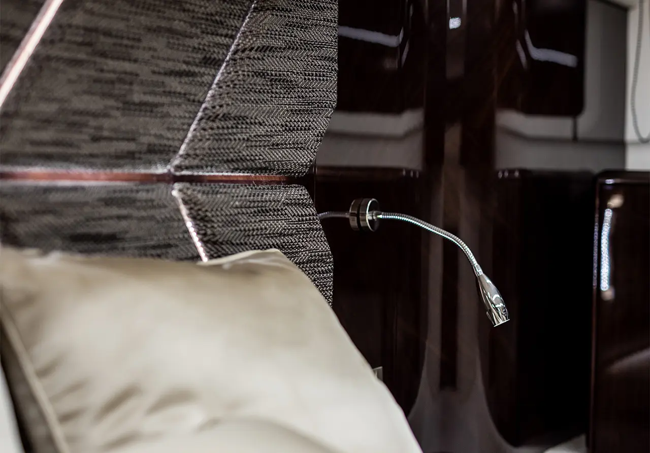 Interior detail of a luxury seat with a flexible reading light and plush cushions in a private jet setting.