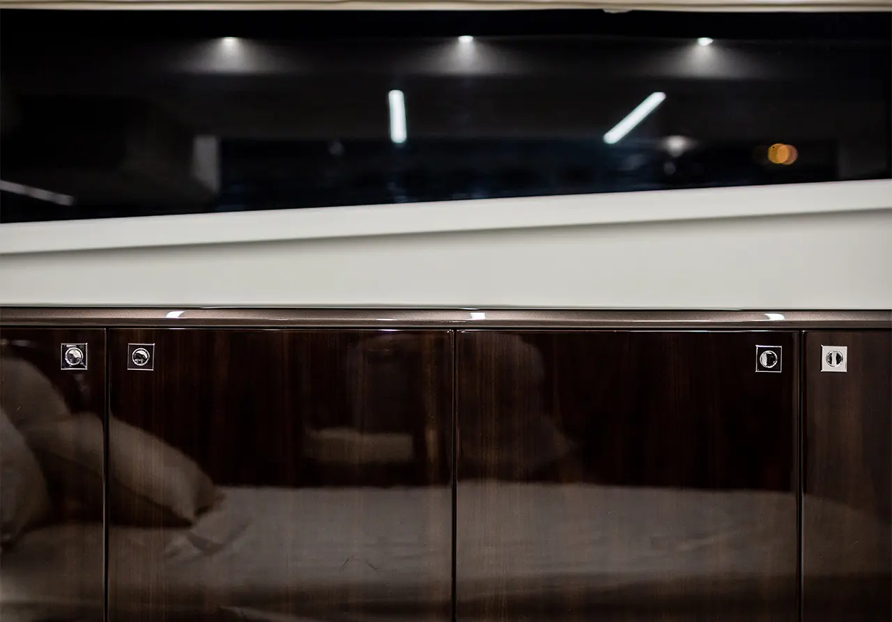 Modern wooden cabinet with metal handles, reflecting ambient lighting, against a dark backdrop with a sleek design.