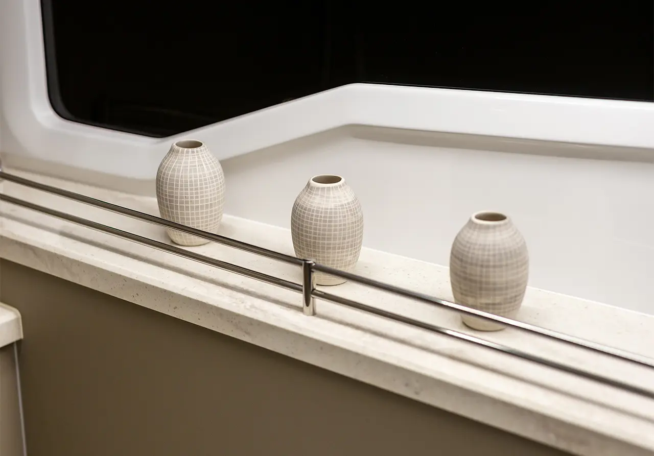 Three ceramic vases with a grid pattern sit on a marble countertop beside a metallic railing, against a black background.