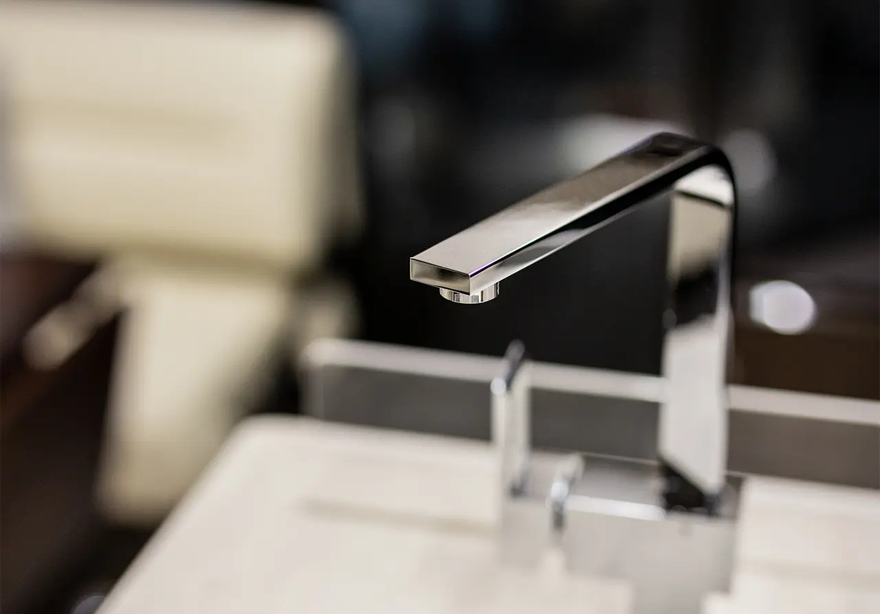 Close-up of a modern chrome tap, showcasing its sleek design against a blurred background of a countertop.