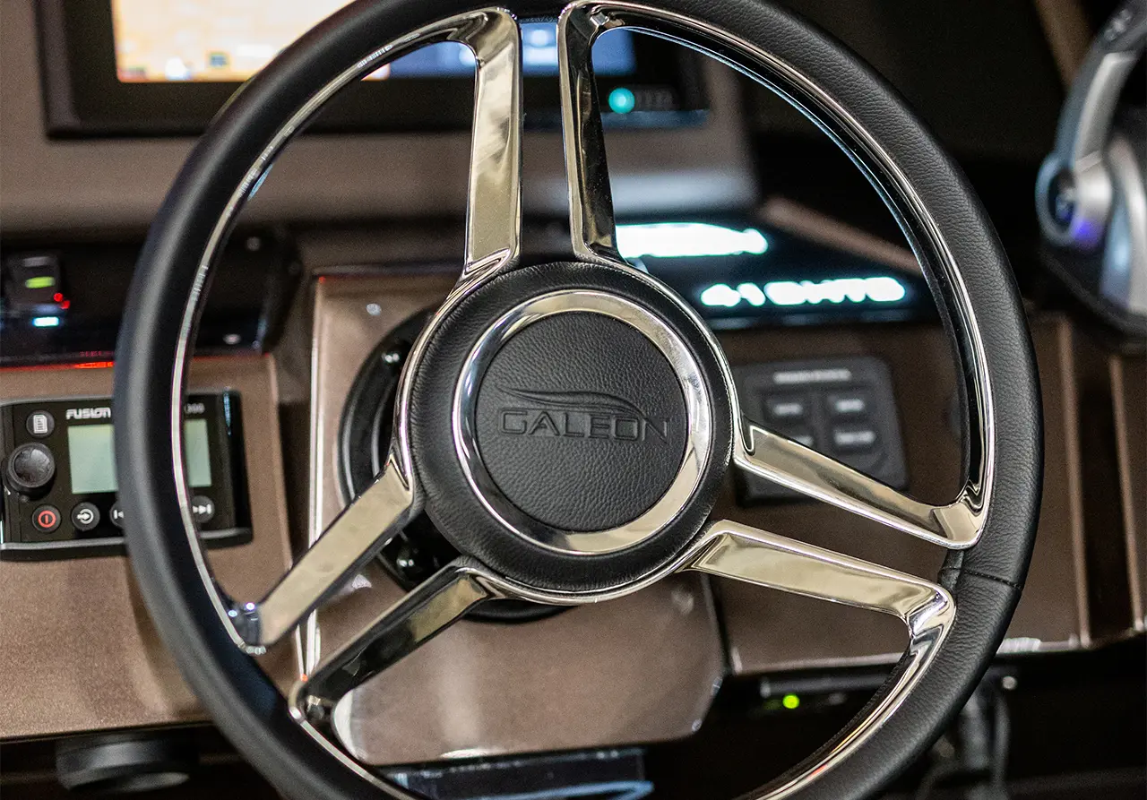 Stylish boat steering wheel with a 'Galeon' logo, featuring dashboard controls and a sleek interior design.