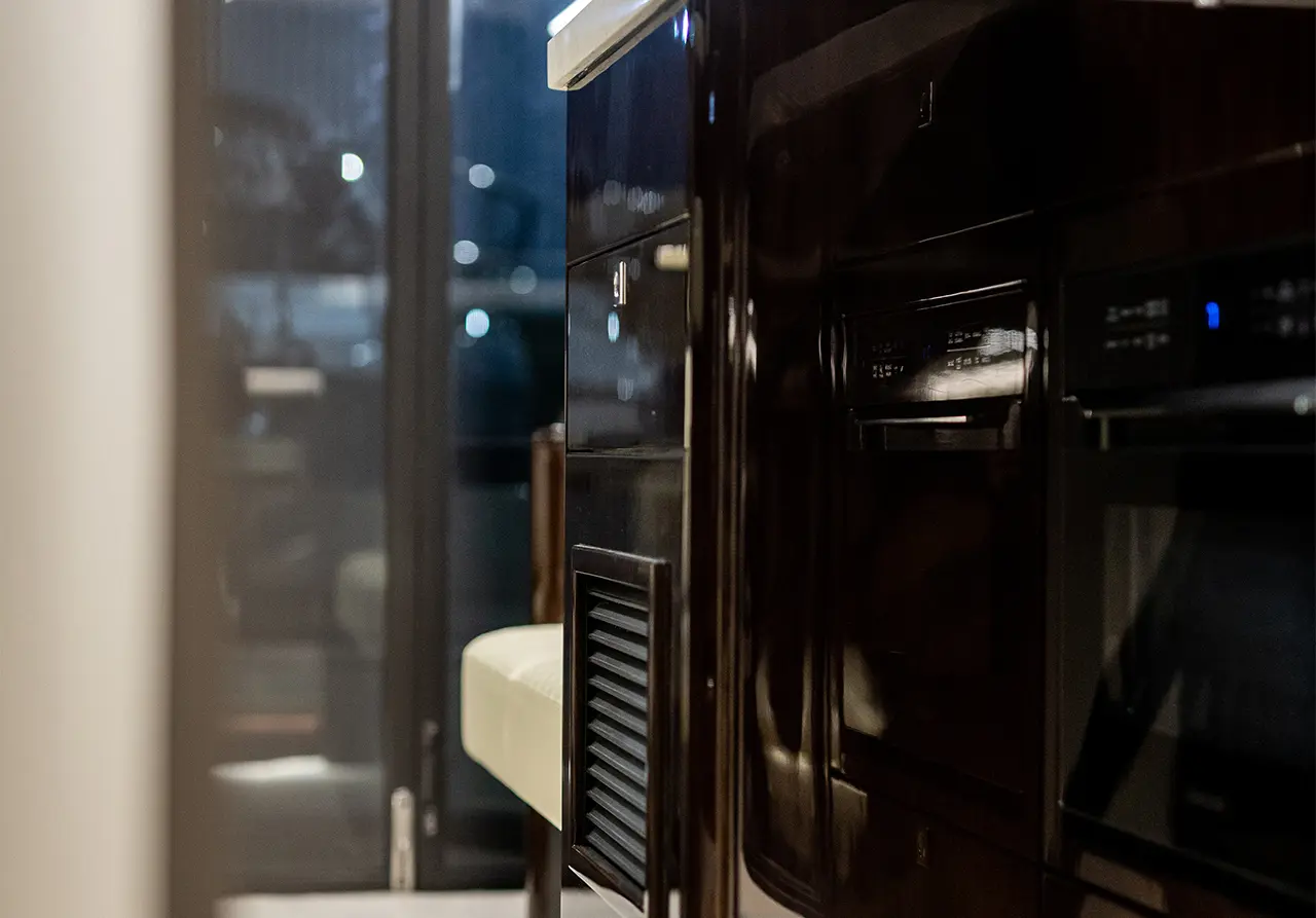 Modern kitchen interior featuring polished cabinetry, a sleek countertop, and a soft seat in low lighting.