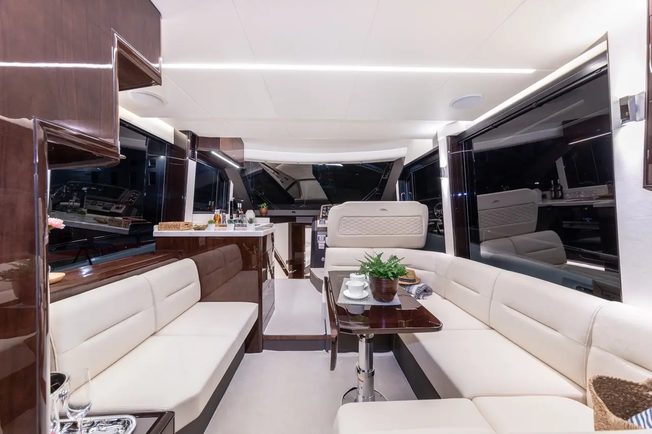 Modern yacht interior featuring elegant seating, polished surfaces, and a well-set dining table with refreshments.