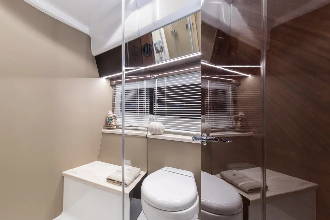 Modern bathroom featuring a white toilet, stone countertop, and decorative items under warm lighting and mirrored walls.