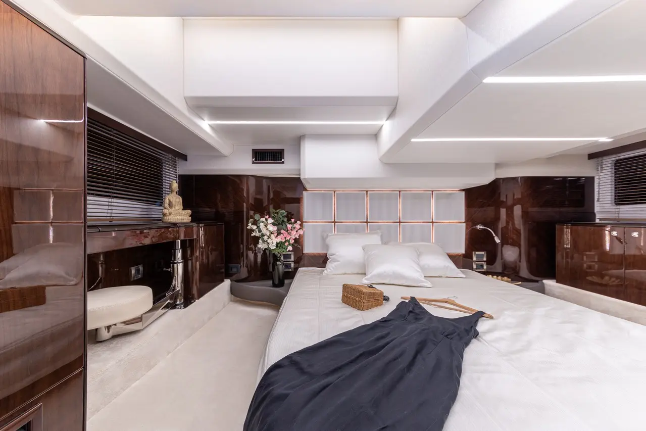 Luxurious bedroom interior with decorative elements, a Buddha statue, flowers, and a dark dress draped over the bed.