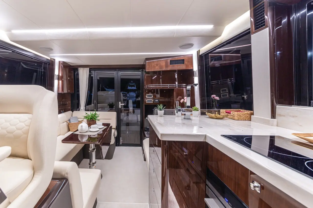 Luxury yacht interior featuring a modern kitchen, dining area, and seating with contemporary decor and soft lighting.