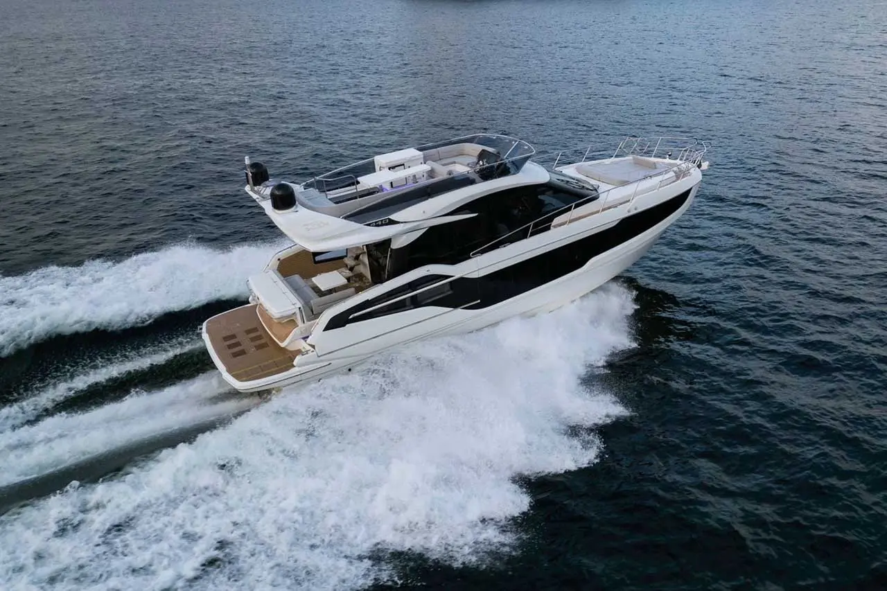 Luxury yacht cruising through water, creating a wake; features sleek design and spacious deck for relaxation.