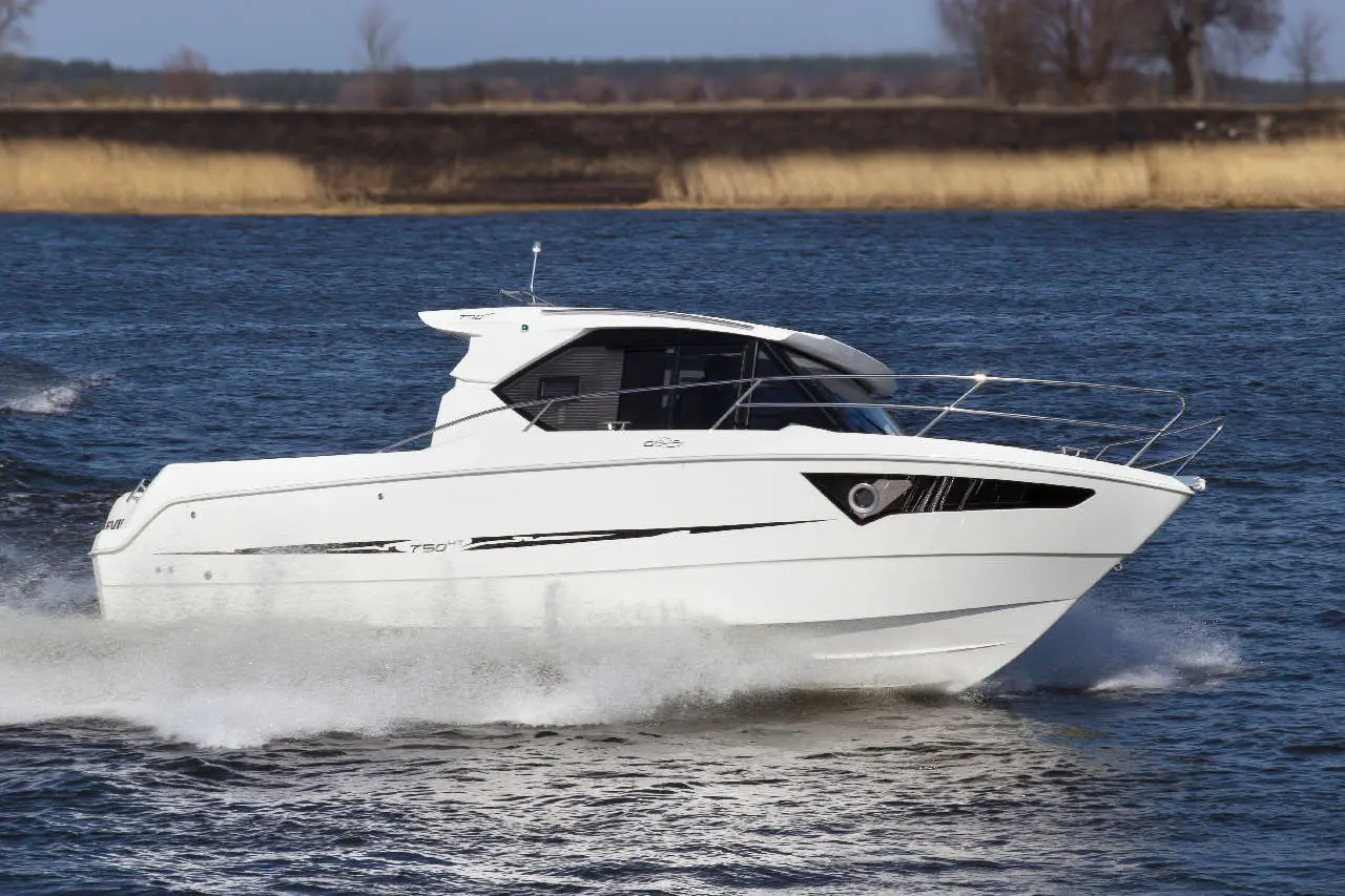 A sleek white motorboat is cruising through a river, creating splashes of water around it. Bright sunlight illuminates the scene.