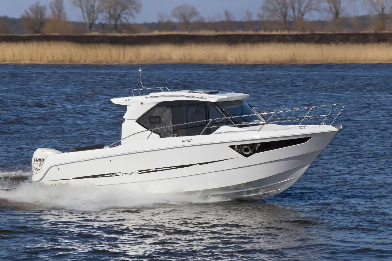 White motorboat cruising on calm water, with grassy banks in the background; 
