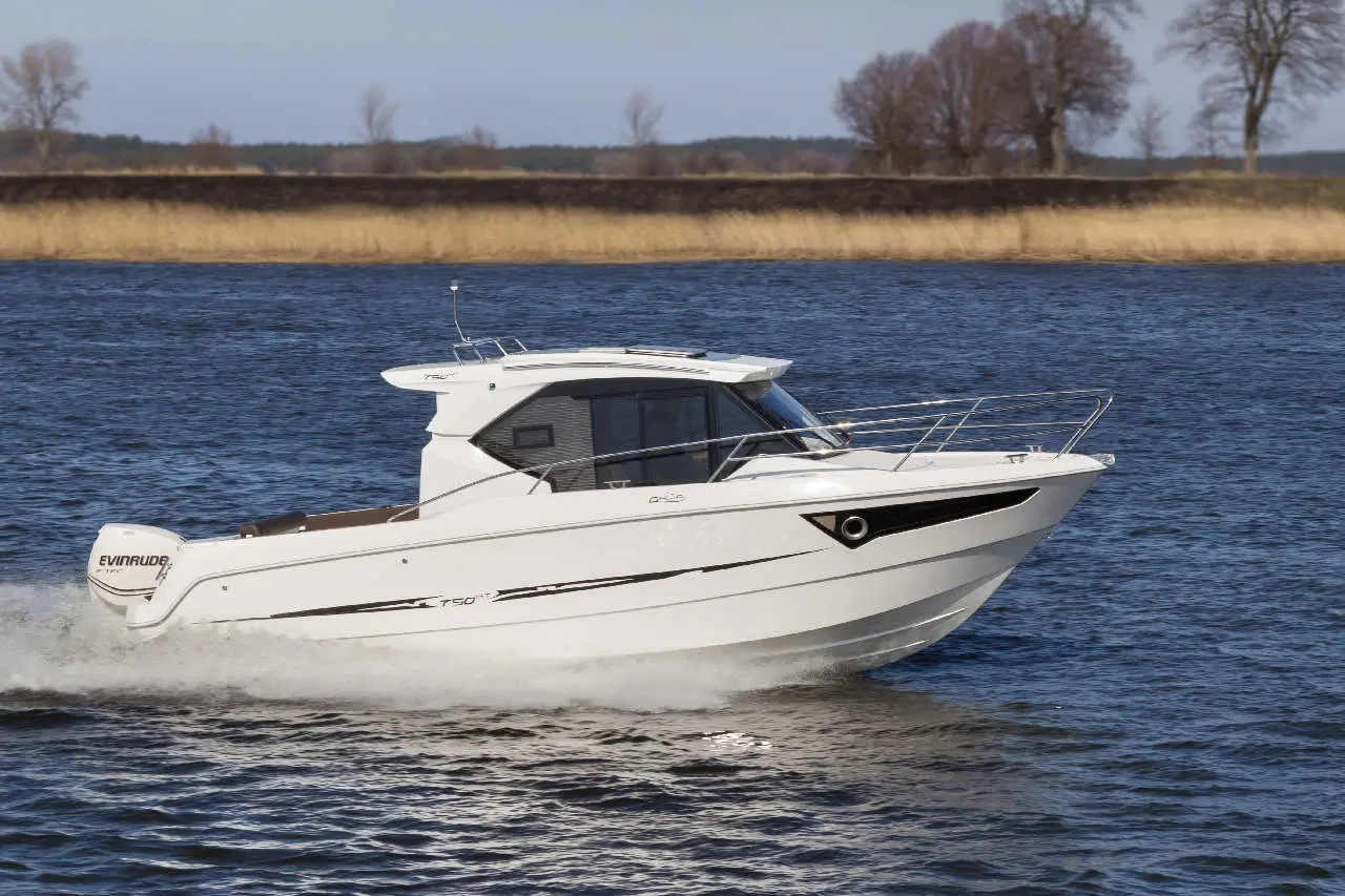 A white motorboat with a sleek design, powered by an Evinrude engine, cruising on calm waters against a tree-lined background.