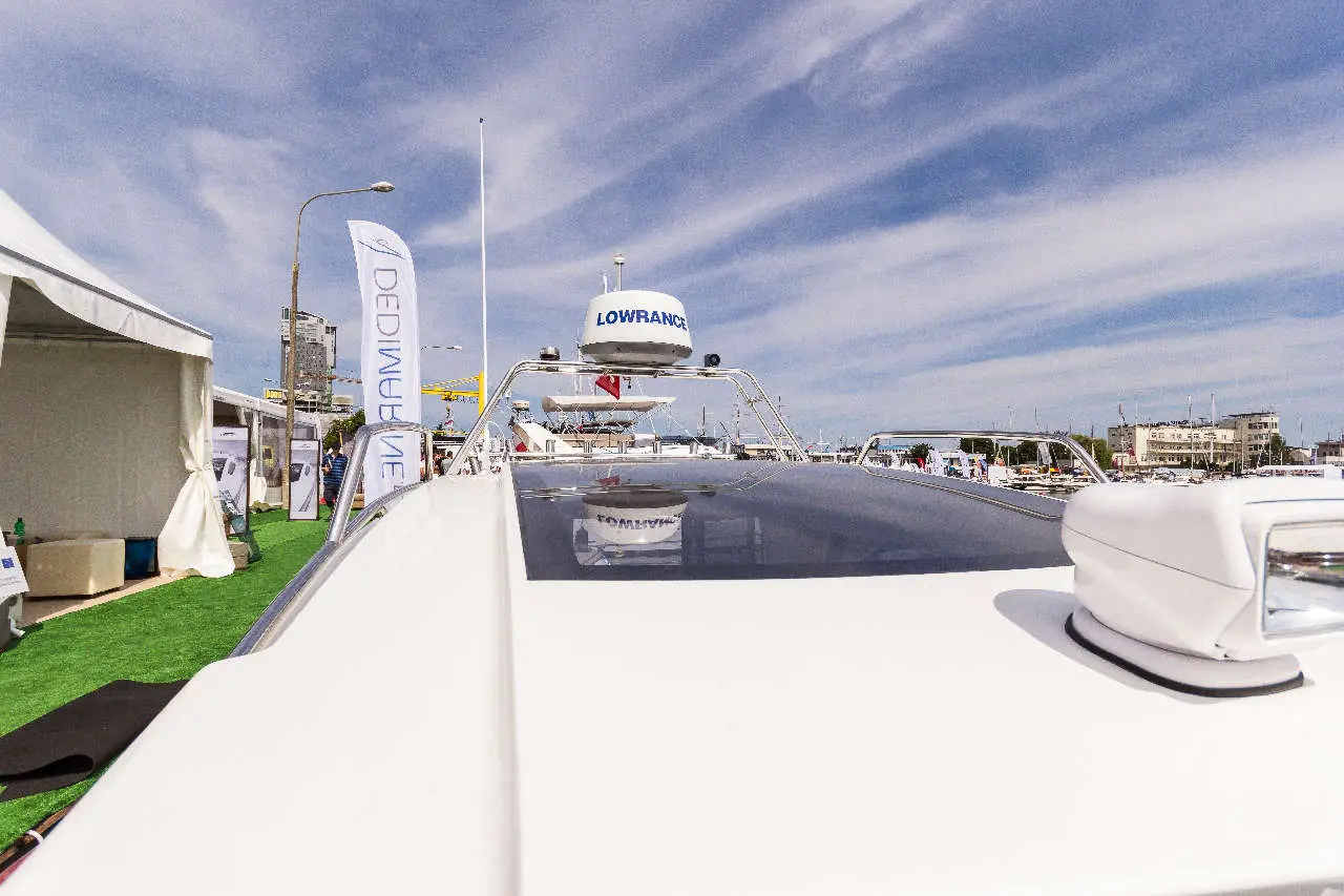 View of a yacht's roof featuring a Lowrance radar system and banners, set against a sunny marina backdrop.