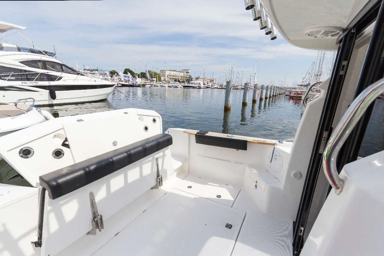 View from a boat showing a marina, moored yachts, and a calm water surface under a clear sky.