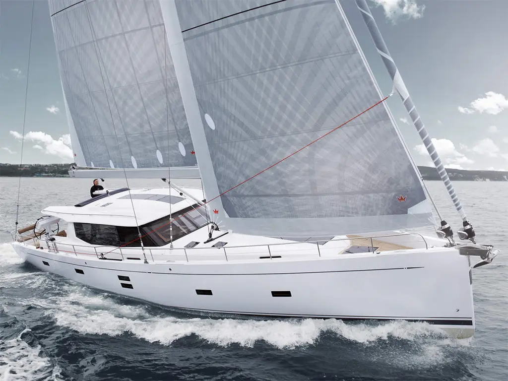A sleek white yacht sails on calm waters, with full sails raised and a sailor adjusting the rigging, under a cloudy sky.