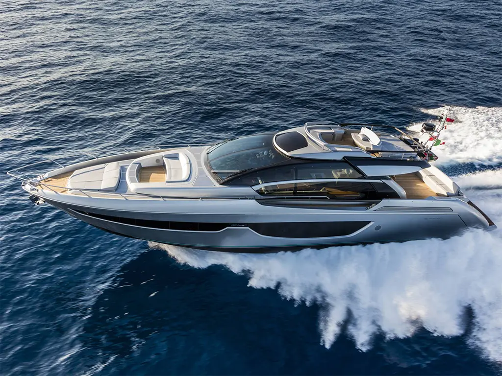 A sleek motor yacht cruises over deep blue water, showcasing luxury design and spacious seating areas on deck.