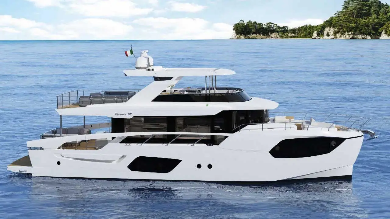 White Navetta 70 luxury yacht on blue sea, with tree-covered cliffs in the background.