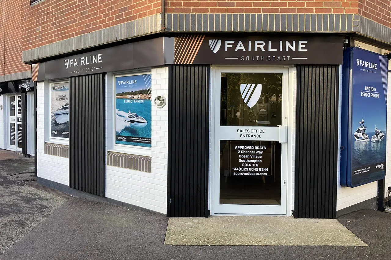 Fairline South Coast sales office exterior featuring entrance signage, promotional boat posters, and contact information.