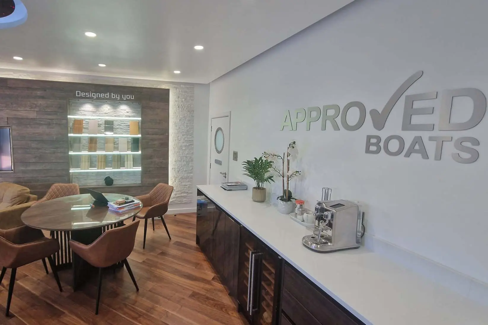 Interior of a stylish office featuring 'Approved Boats' signage, a round table, contemporary chairs, and design samples.