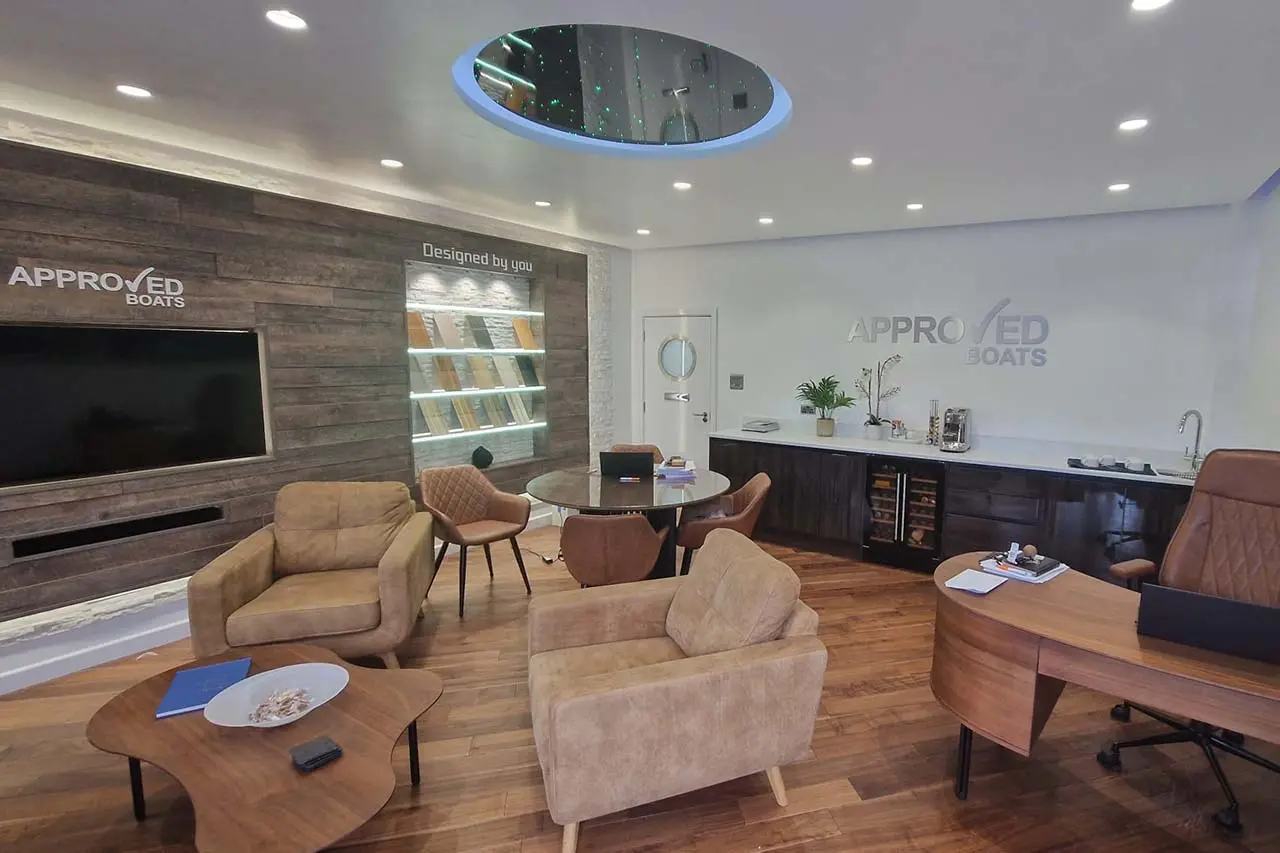 Modern office interior featuring seating, a coffee area, a wall-mounted TV, and 