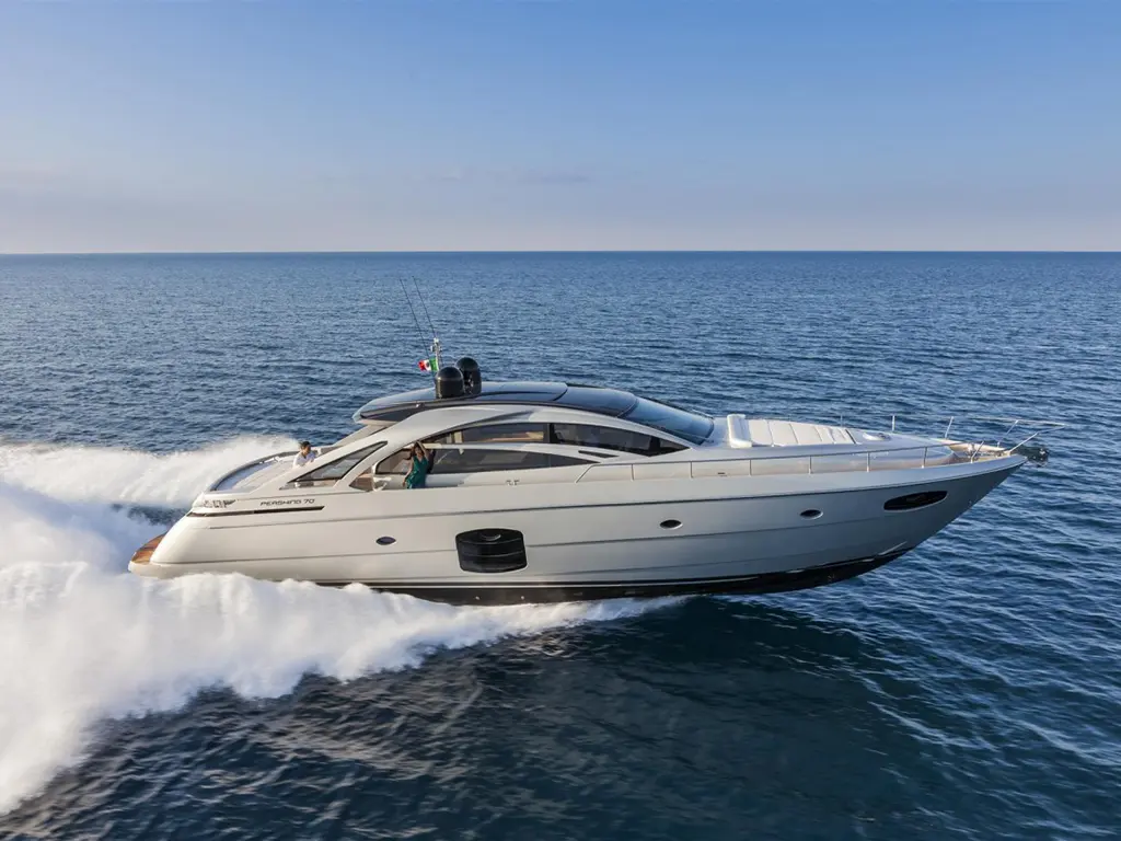 A sleek motor yacht speeding across the ocean, leaving a wake, with a crew member visible at the helm.