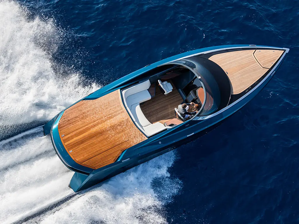 Aerial view of a sleek motorboat with wooden decking, cruising through deep blue waters with two passengers on board.