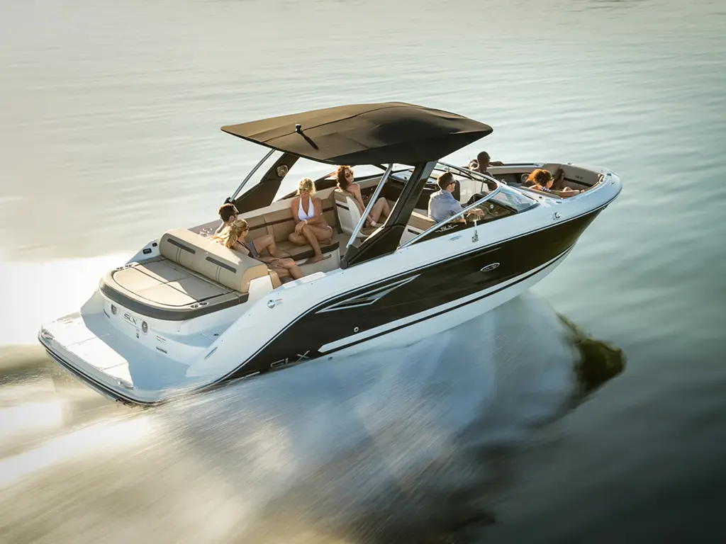 A sleek boat with six people on board, cruising on calm waters under a sunshade. Clear skies reflect on the water.