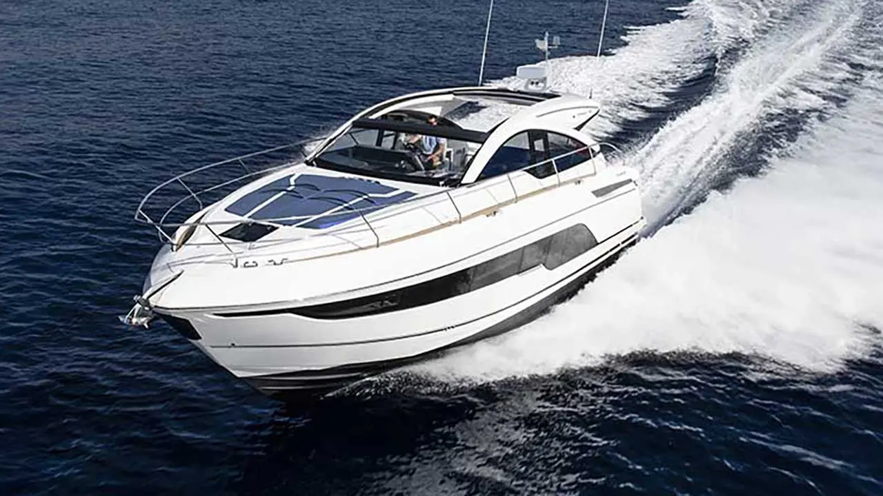 White luxury motor yacht speeding across deep blue sea, leaving a foamy wake.