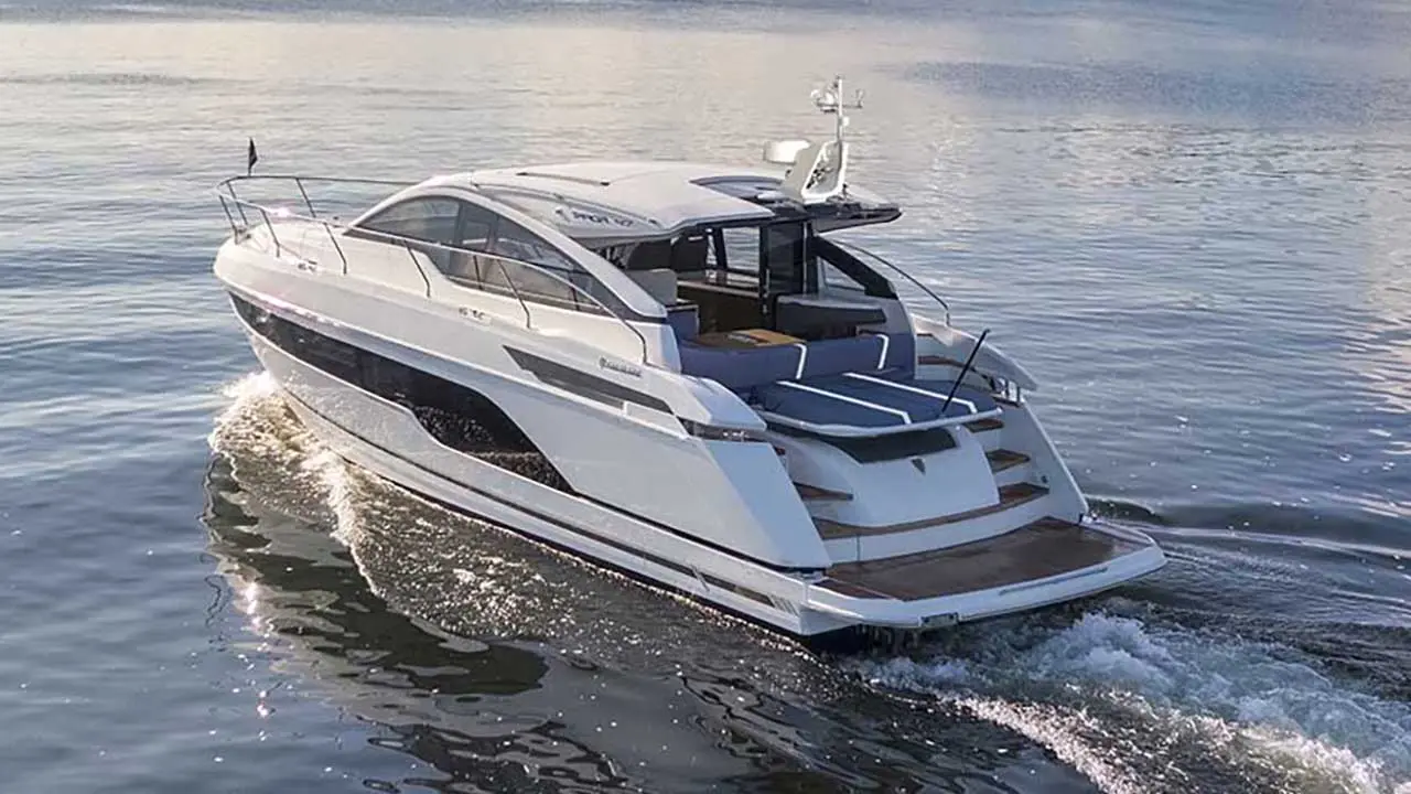 White luxury motor yacht cruising across calm blue water, leaving a foamy wake.