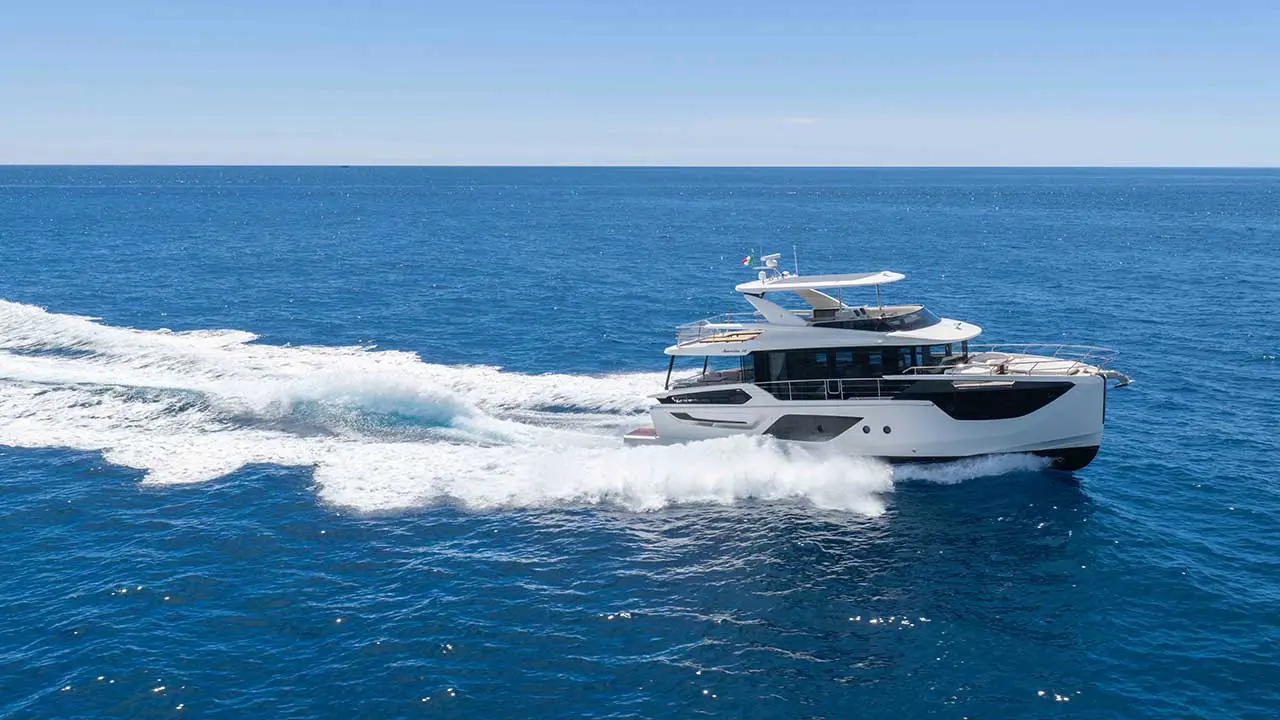 Luxury motor yacht speeding across the deep blue sea, creating a white wake under a clear sky.