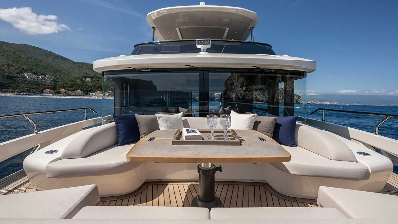 Luxury yacht aft deck with dining table, cushioned seating and sea views of Montenegro’s mountainous coastline