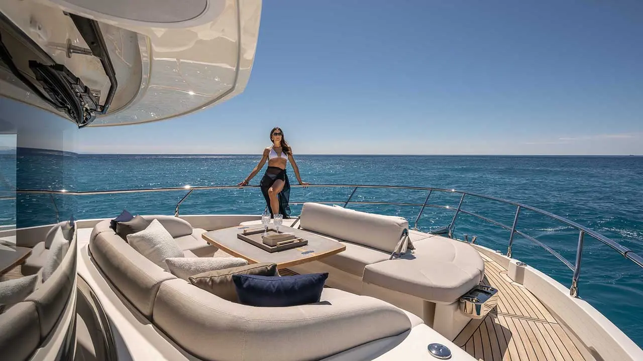 Woman in swimwear stands on the bow of a luxury yacht overlooking the blue sea.