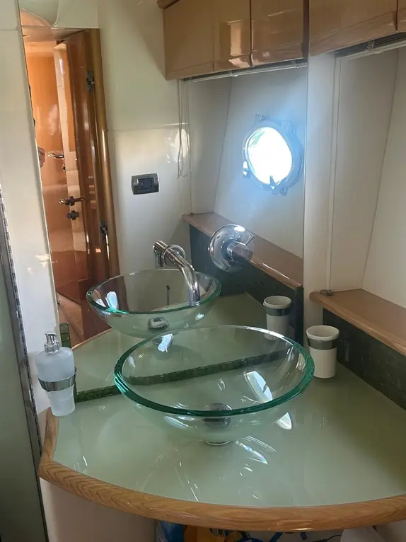 Modern bathroom interior featuring two glass vessel sinks, a polished faucet, and green mosaic tiles.