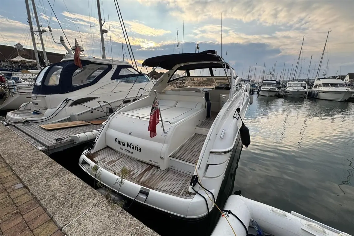 A white motorboat named "Anna Maria" docked at Port Solent, surrounded by yachts and a cloudy sky reflecting on the water.
