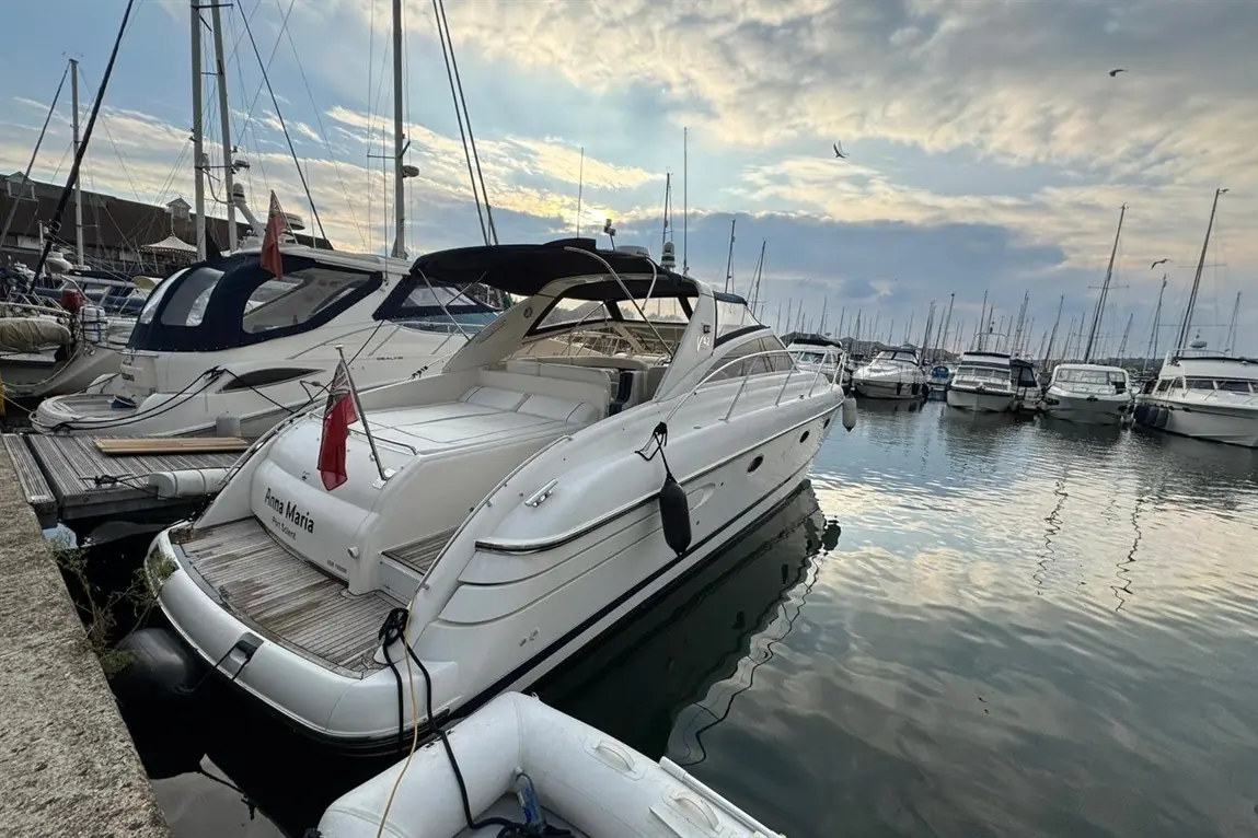 Luxury boat "Anna Maria" docked at a marina surrounded by other yachts under a cloudy sky.