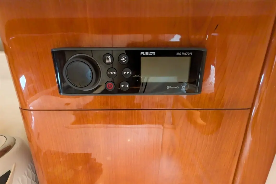 Fusion MS-RA70N audio control panel on wooden surface, featuring buttons, a display, and Bluetooth connectivity.