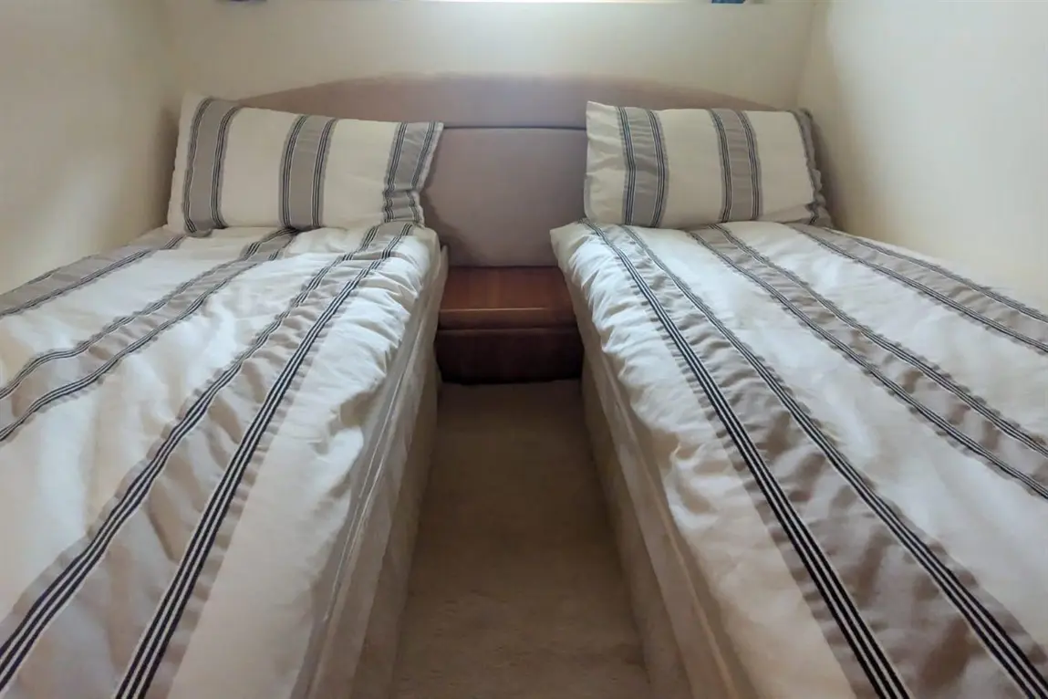 Two single beds with striped bedding placed parallel to each other, featuring a small wooden nightstand in between.