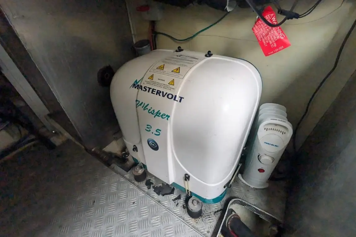 Mastervolt Whisper 3.5 generator in a boat compartment, with warning label and nearby electrical device visible.