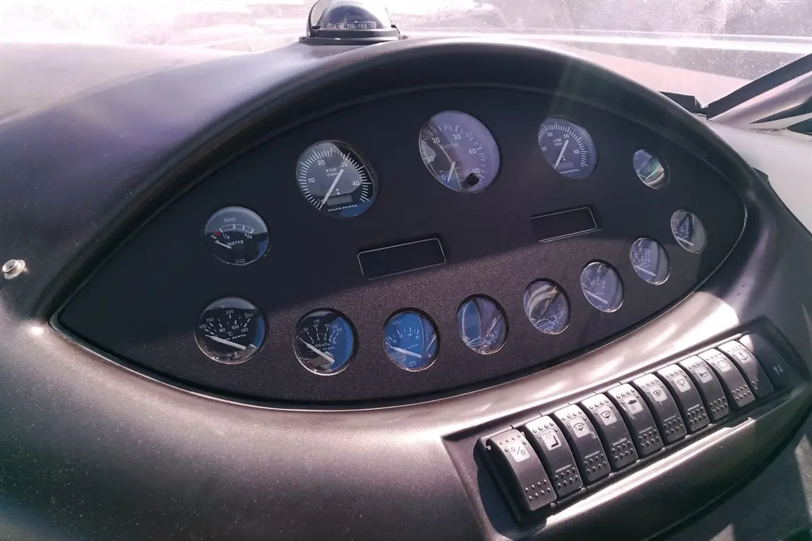 Dashboard of a boat with various gauges for fuel, water, and engine metrics, plus toggle switches for operations.