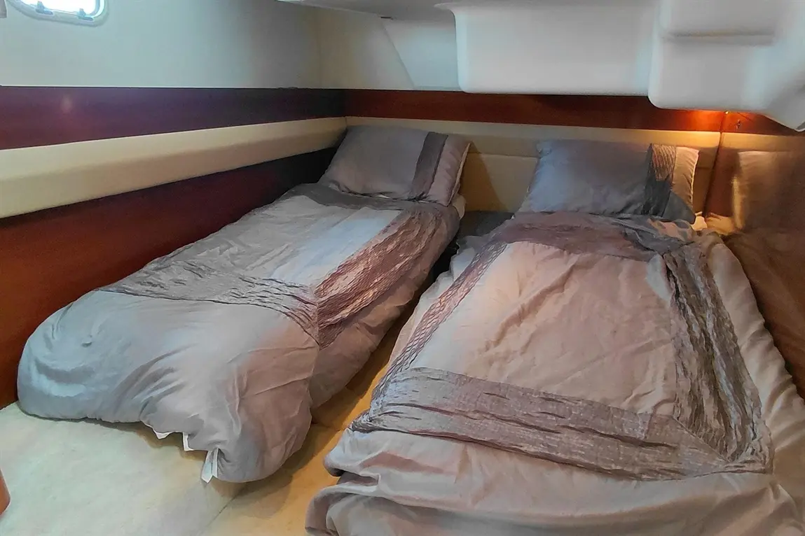 Two single beds with grey bedding arranged in a compact cabin, featuring wooden walls and soft lighting.