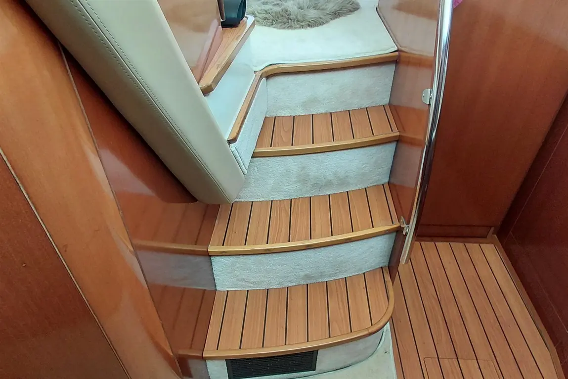 Wooden staircase leading up, featuring padded railing, carpeted steps, and a wooden floor in an indoor setting.