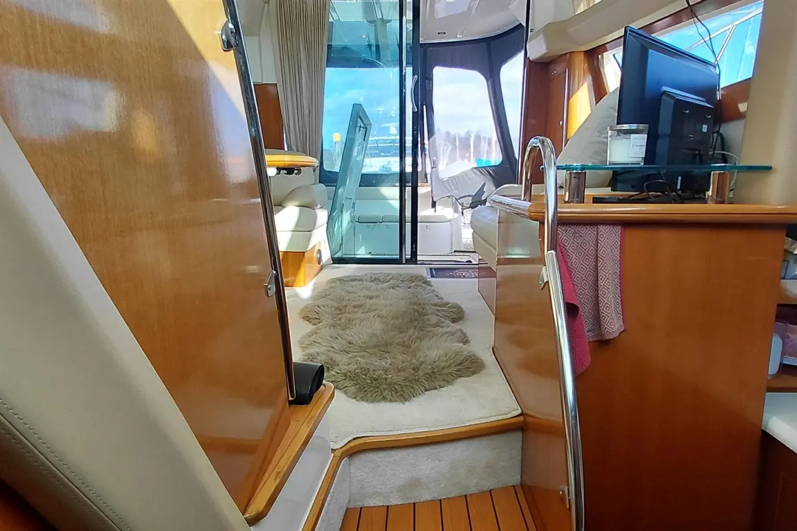 Interior view of a yacht featuring a plush rug, wooden accents, and a glass door leading to an outside area.