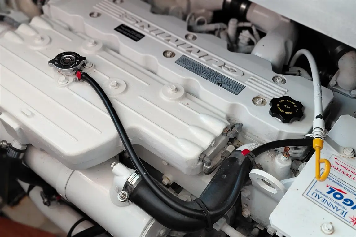 Engine components with a white valve cover, hoses, and a black cap visible, alongside labels and gauges for diagnostics.